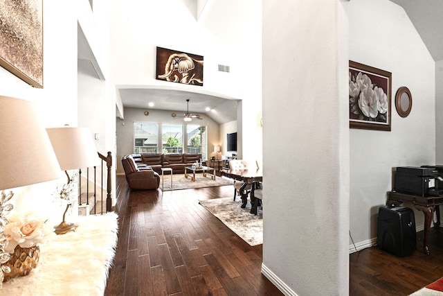 hall with dark wood-style floors, visible vents, high vaulted ceiling, and baseboards