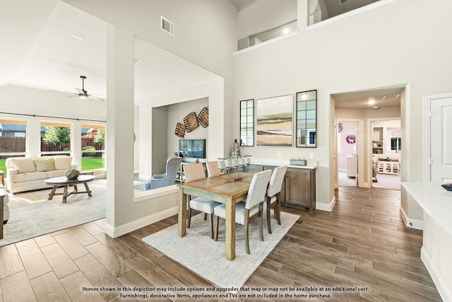 dining room with a ceiling fan, visible vents, high vaulted ceiling, and dark wood finished floors