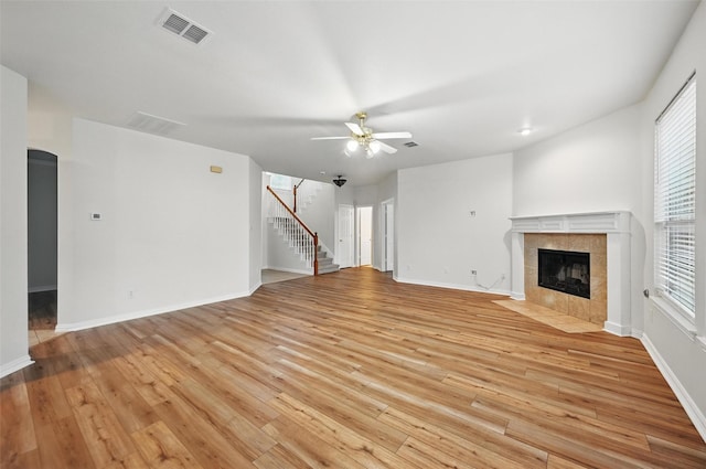 1405 Blue Gill Ln, Crowley, TX 76036 - unfurnished living room with a ceiling fan, baseboards, a tiled fireplace, and light wood-type flooring