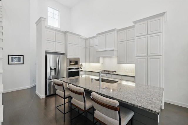 kitchen with appliances with stainless steel finishes, light stone countertops, baseboards, and a sink