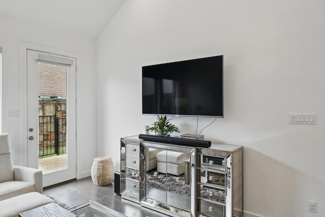 living area with a wealth of natural light, wood finished floors, vaulted ceiling, and baseboards