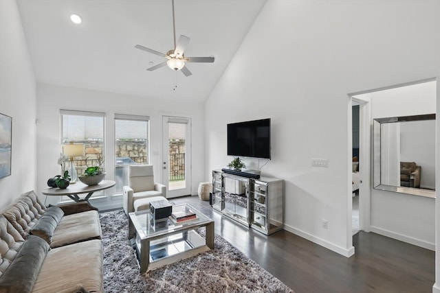 living room featuring ceiling fan, baseboards, high vaulted ceiling, and dark wood-type flooring