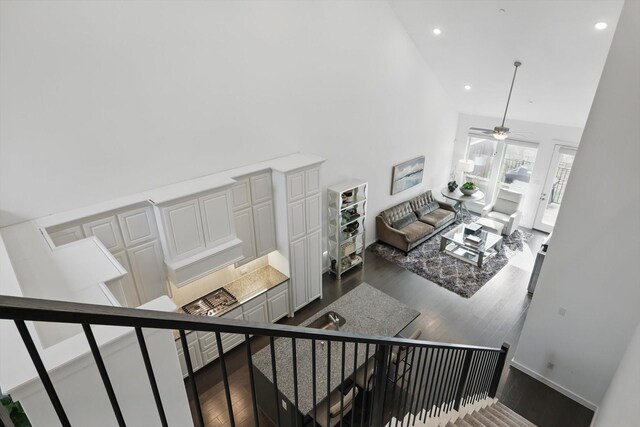 staircase featuring recessed lighting, wood finished floors, ceiling fan, and a high ceiling