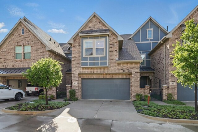 view of front of home with driveway, a standing seam roof, roof with shingles, brick siding, and a garage