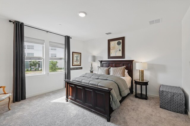 bedroom with baseboards, visible vents, and light carpet