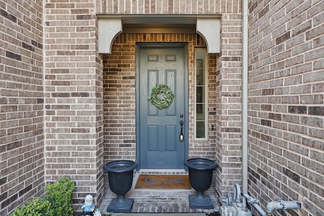 view of exterior entry featuring brick siding