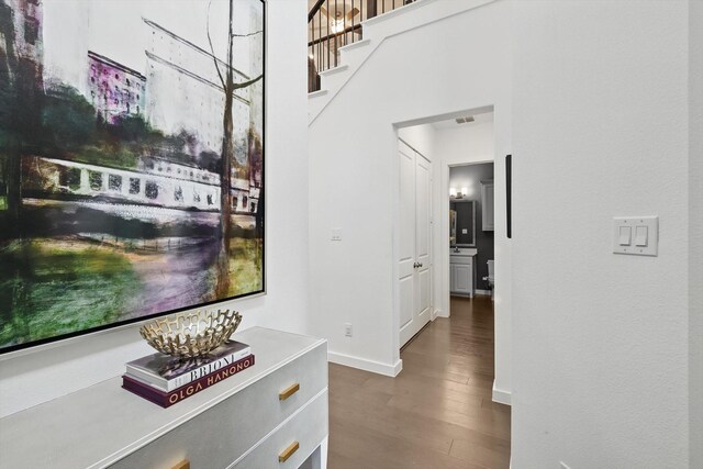 hallway featuring baseboards, visible vents, wood finished floors, and stairway