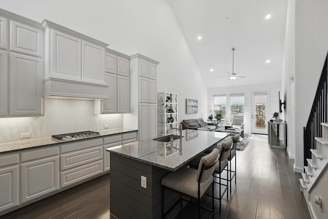 kitchen with a sink, stainless steel gas stovetop, ceiling fan, high vaulted ceiling, and open floor plan