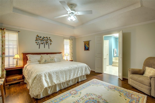 bedroom with connected bathroom, a raised ceiling, a ceiling fan, baseboards, and wood finished floors