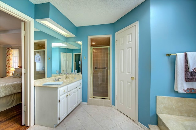 ensuite bathroom featuring baseboards, a shower stall, ensuite bath, and double vanity