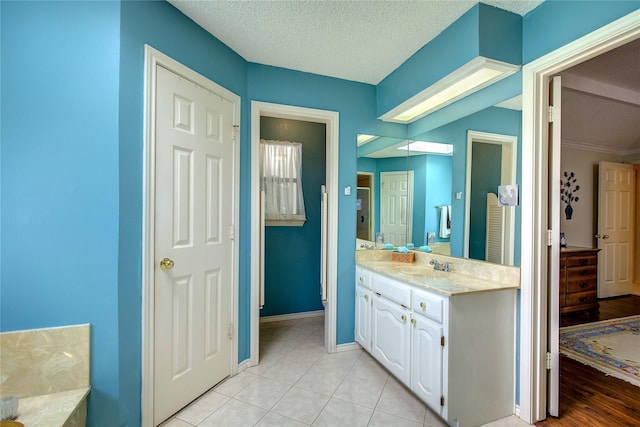 full bathroom with tile patterned floors, a textured ceiling, vanity, and baseboards