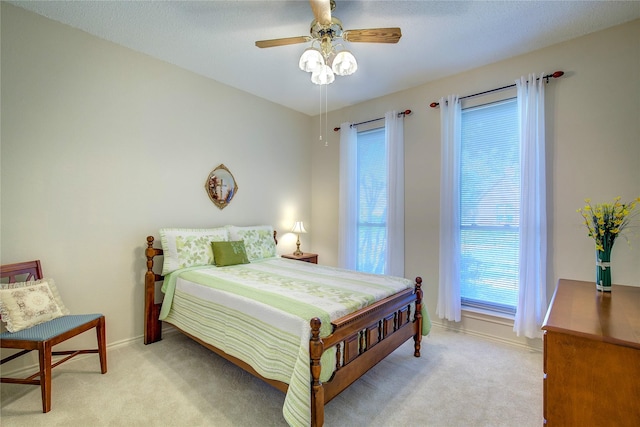 bedroom with ceiling fan, light carpet, and baseboards