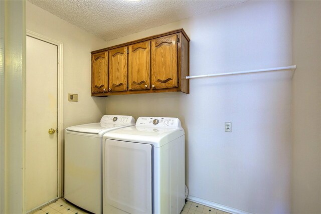 washroom with washing machine and dryer, a textured ceiling, cabinet space, and light floors