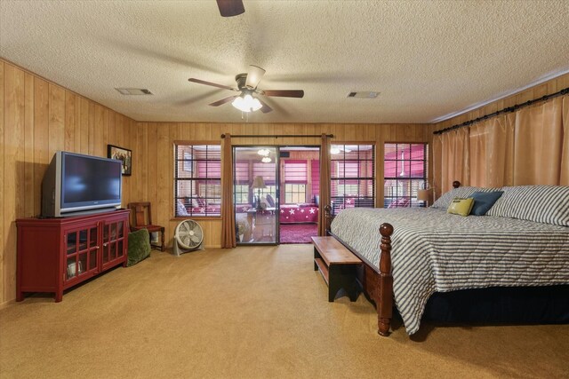 bedroom featuring a textured ceiling, wood walls, visible vents, ceiling fan, and carpet