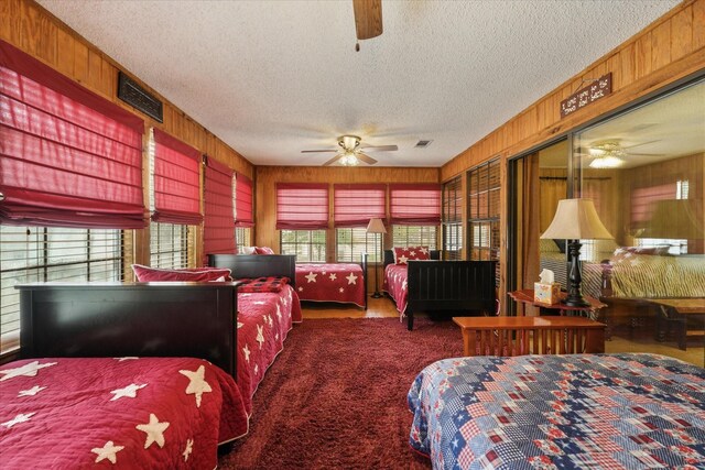 carpeted bedroom featuring visible vents, a textured ceiling, and wooden walls