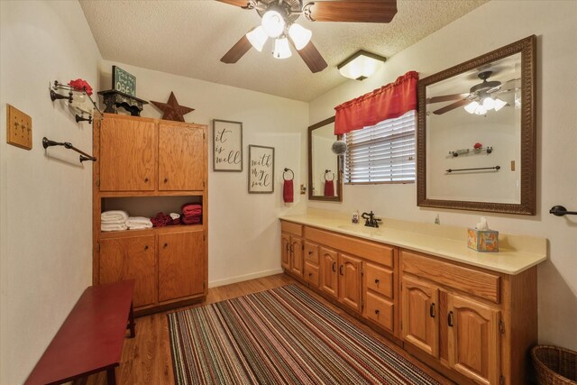 bathroom with a textured ceiling, wood finished floors, vanity, and a ceiling fan