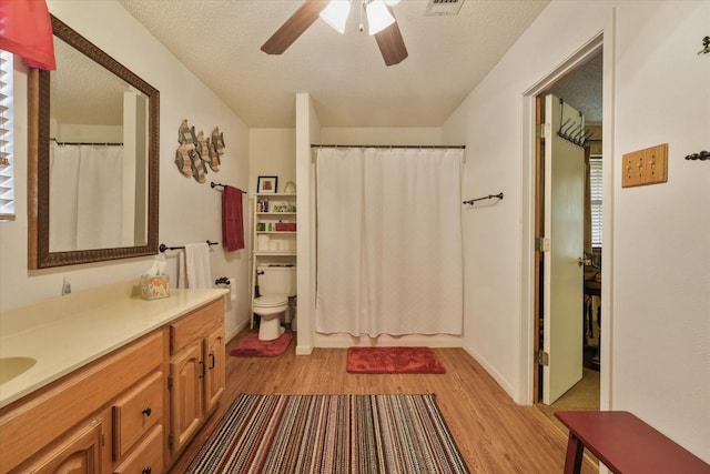 bathroom featuring toilet, vanity, a ceiling fan, and wood finished floors