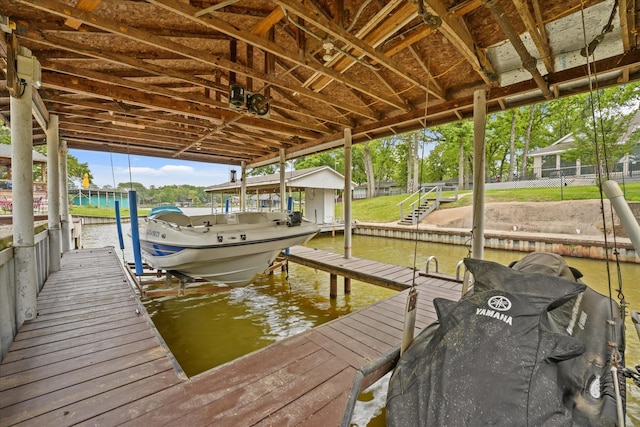 view of dock featuring a water view, boat lift, and fence