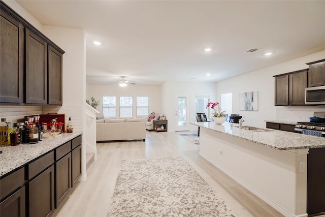 462 Pleasant Hill Ln, Fate, TX 75189 - kitchen with dark brown cabinets, a sink, light wood-style floors, stainless steel microwave, and visible vents
