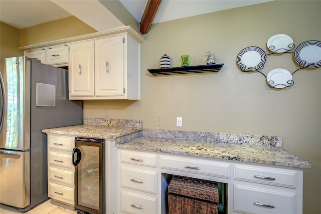 kitchen featuring light stone countertops, beam ceiling, wine cooler, white cabinetry, and freestanding refrigerator