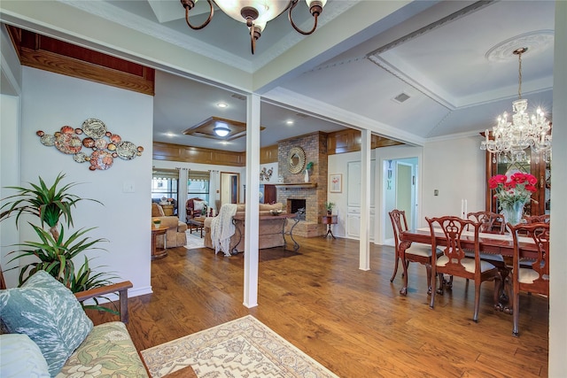 dining space featuring visible vents, ornamental molding, a fireplace, wood finished floors, and a notable chandelier