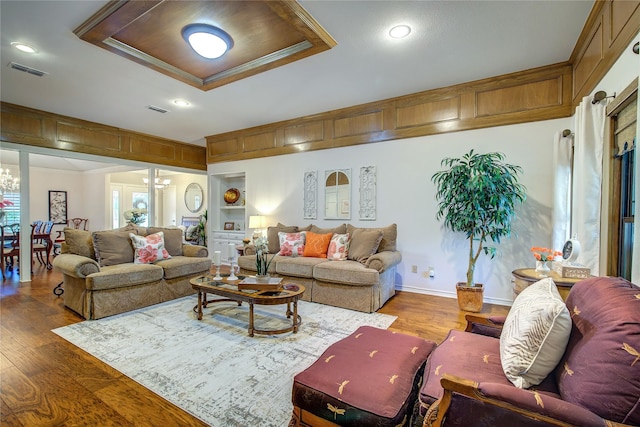 living area with wood finished floors, visible vents, ornamental molding, and baseboards