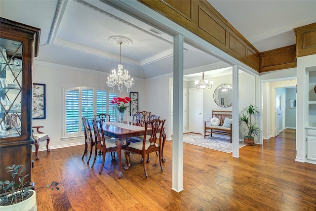 dining area featuring an inviting chandelier, a raised ceiling, wood finished floors, and baseboards