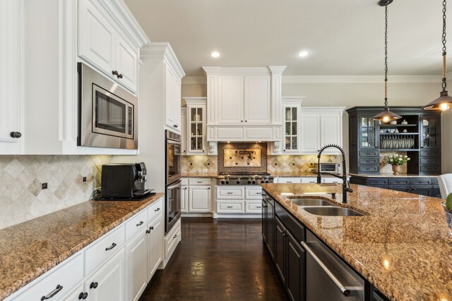 kitchen featuring light stone countertops, glass insert cabinets, appliances with stainless steel finishes, a sink, and white cabinetry