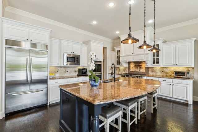 kitchen featuring white cabinetry, crown molding, glass insert cabinets, a sink, and built in appliances