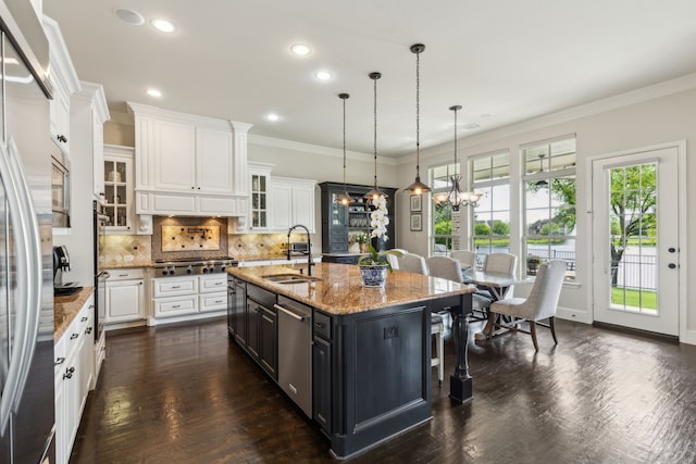 kitchen featuring a breakfast bar area, white cabinets, a sink, a kitchen island with sink, and a notable chandelier