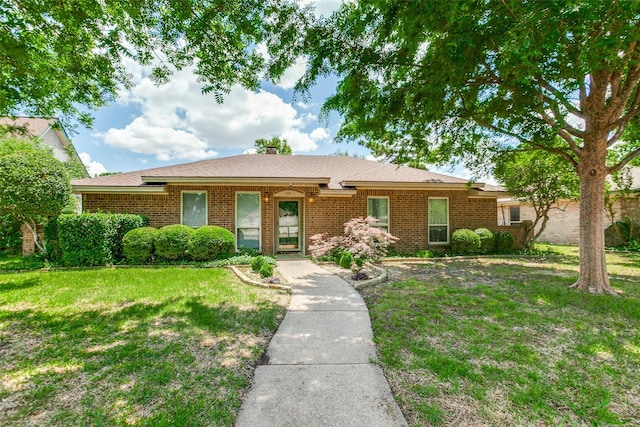 ranch-style house with a front yard, brick siding, and a chimney