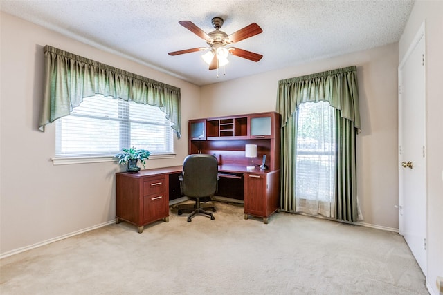 office space with light carpet, ceiling fan, baseboards, and a textured ceiling