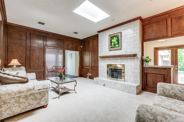 living area featuring a fireplace, a skylight, carpet flooring, ornamental molding, and a textured ceiling