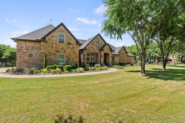 english style home with a front lawn and stone siding