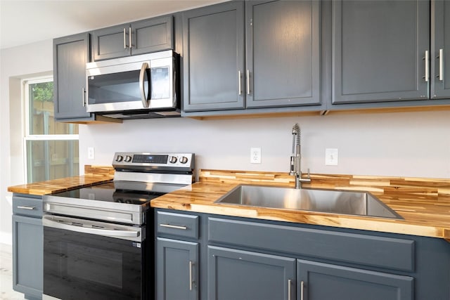 kitchen with butcher block counters, stainless steel appliances, and a sink