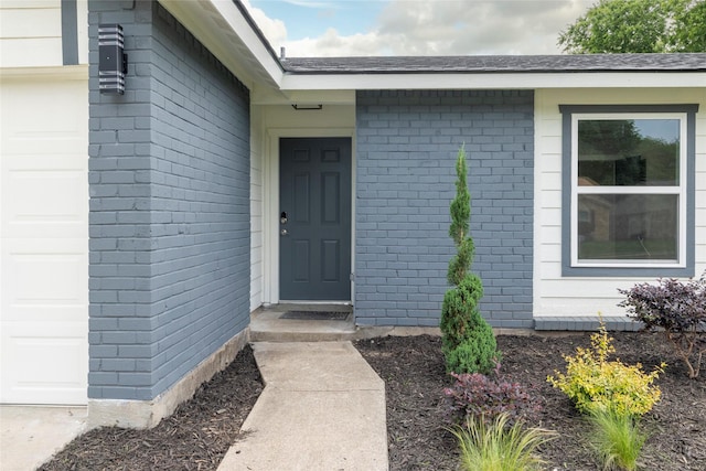 entrance to property with brick siding and a garage