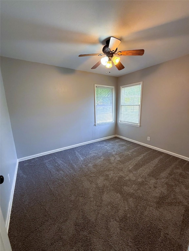 spare room with ceiling fan, dark carpet, and baseboards
