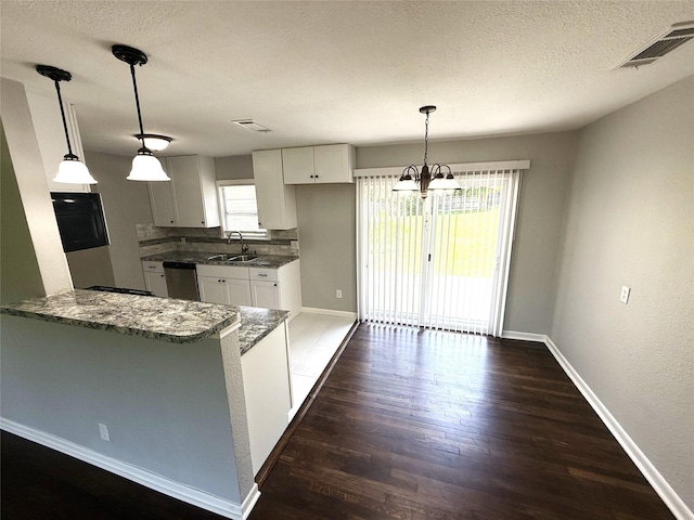 kitchen featuring dark stone countertops, visible vents, baseboards, dishwasher, and dark wood finished floors