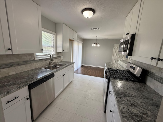 kitchen with decorative backsplash, stainless steel appliances, a sink, white cabinetry, and visible vents