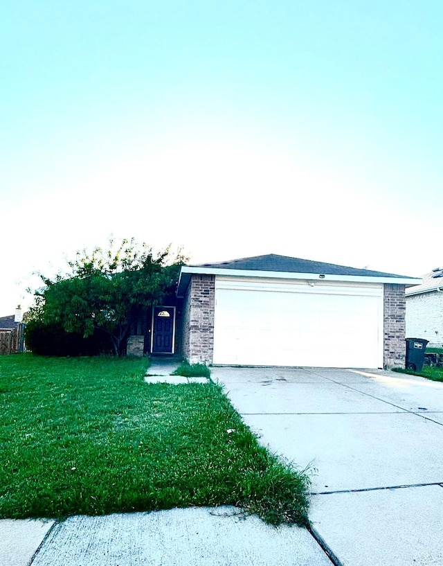 view of front of property with brick siding, a front lawn, driveway, and an attached garage