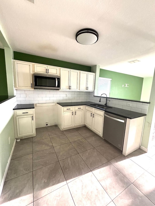 kitchen featuring a textured ceiling, stainless steel appliances, decorative backsplash, and a sink