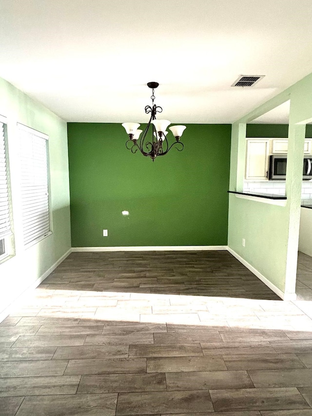 interior space featuring a chandelier, wood finished floors, visible vents, and baseboards