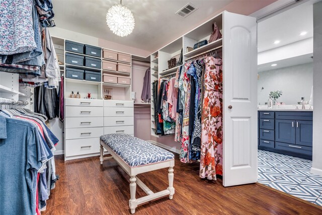 spacious closet featuring a sink, an inviting chandelier, visible vents, and wood finished floors