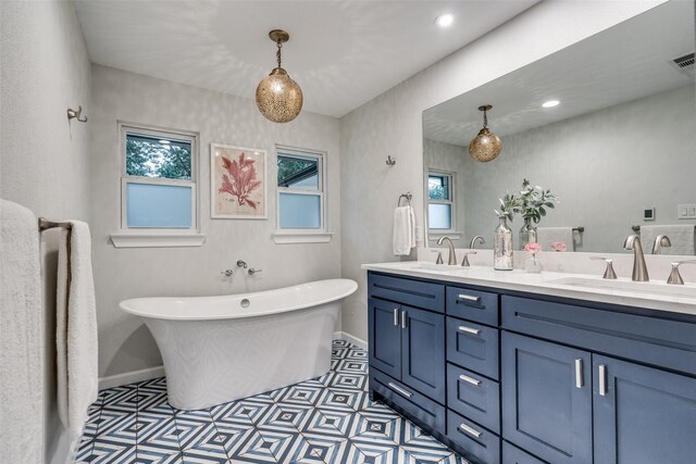 full bathroom with baseboards, double vanity, a soaking tub, and a sink