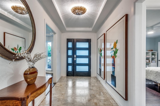 entrance foyer featuring a tray ceiling and baseboards