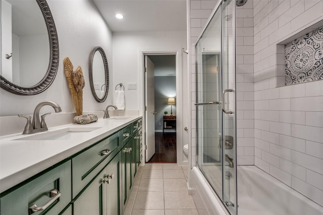 full bath featuring tile patterned floors, combined bath / shower with glass door, toilet, and a sink