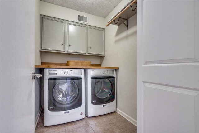 washroom with cabinet space, washing machine and clothes dryer, visible vents, baseboards, and a textured ceiling