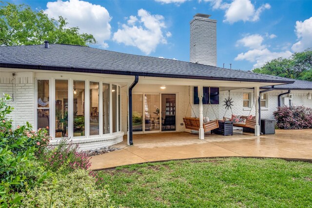 rear view of property featuring an outdoor hangout area, a chimney, a patio area, roof with shingles, and brick siding