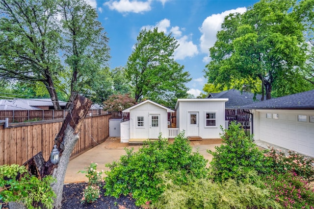 back of house featuring fence, an outdoor structure, and a garage