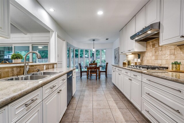 kitchen featuring stainless steel appliances, under cabinet range hood, backsplash, a sink, and white cabinetry